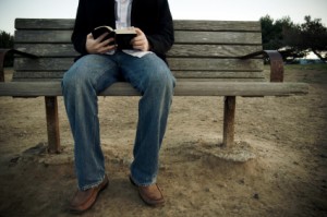 Man on a bench reading his Bible